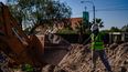 Con la iglesia de El Challao de fondo, un operario trabaja en un zanjeo como los que requerirá el nuevo sistema de provisión de agua potable en la zona norte del pedemonte de Mendoza