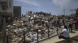Personas son vistas sobre los escombros de un edificio derrumbado en La Guaira.
