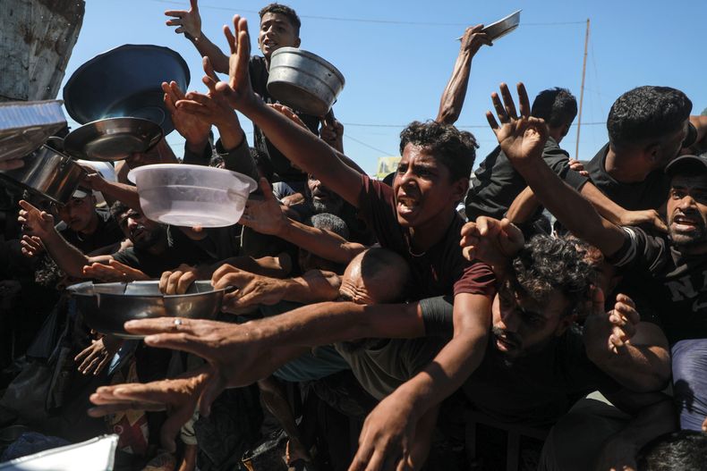 Palestinos desplazados sostienen sus recipientes vacíos mientras esperan para recibir alimentos gratuitos en un centro de distribución, en la ciudad de Khan Younis, en el sur de la Franja de Gaza. (Xinhua/Rizek Abdeljawad)